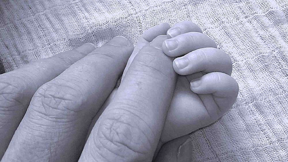 Eine Babyhand umfasst einen Finger eines Erwachsenen
